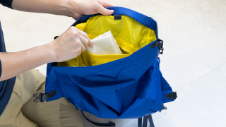 バックパックのポケットから中のものを取り出している様子